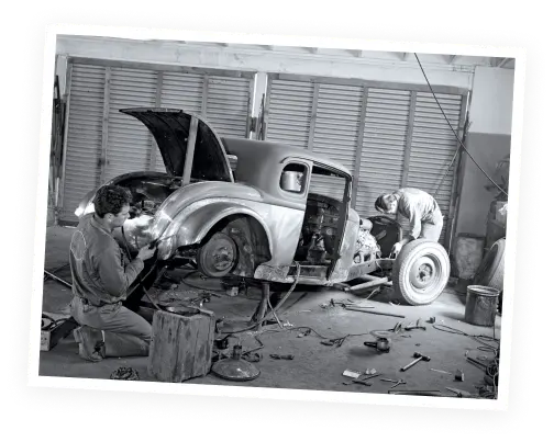 a vintage photo of mechanics working on an old-fashioned car